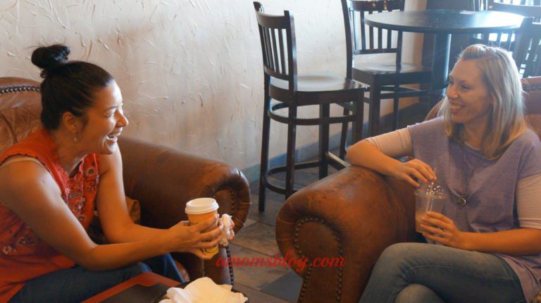 Two people sitting in a room with drinks and smoking.