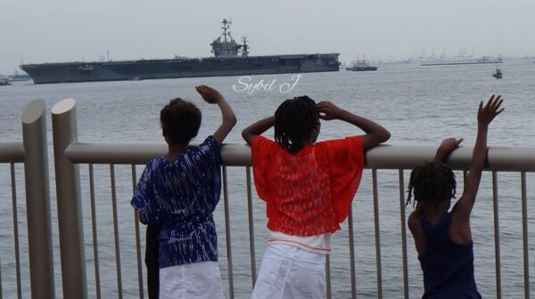 Two people looking out over the water at a boat.