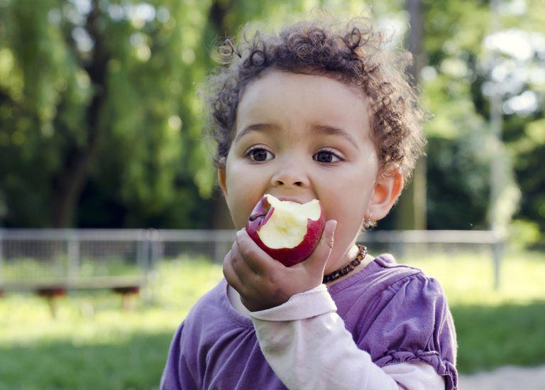A child eating an apple in the park.