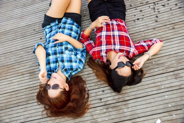 Two women laying on the ground wearing sunglasses.