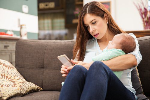 A woman sitting on the couch with her baby.