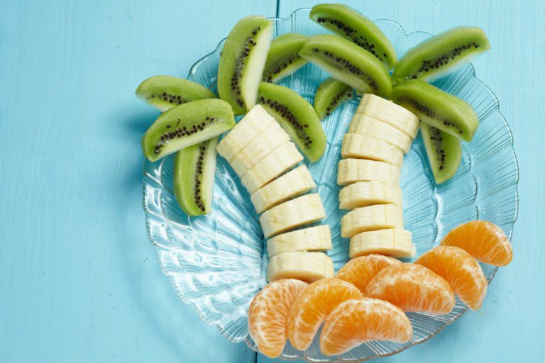 A plate of fruit cut into palm trees and oranges.