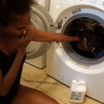 A woman is looking at the clothes in the dryer.