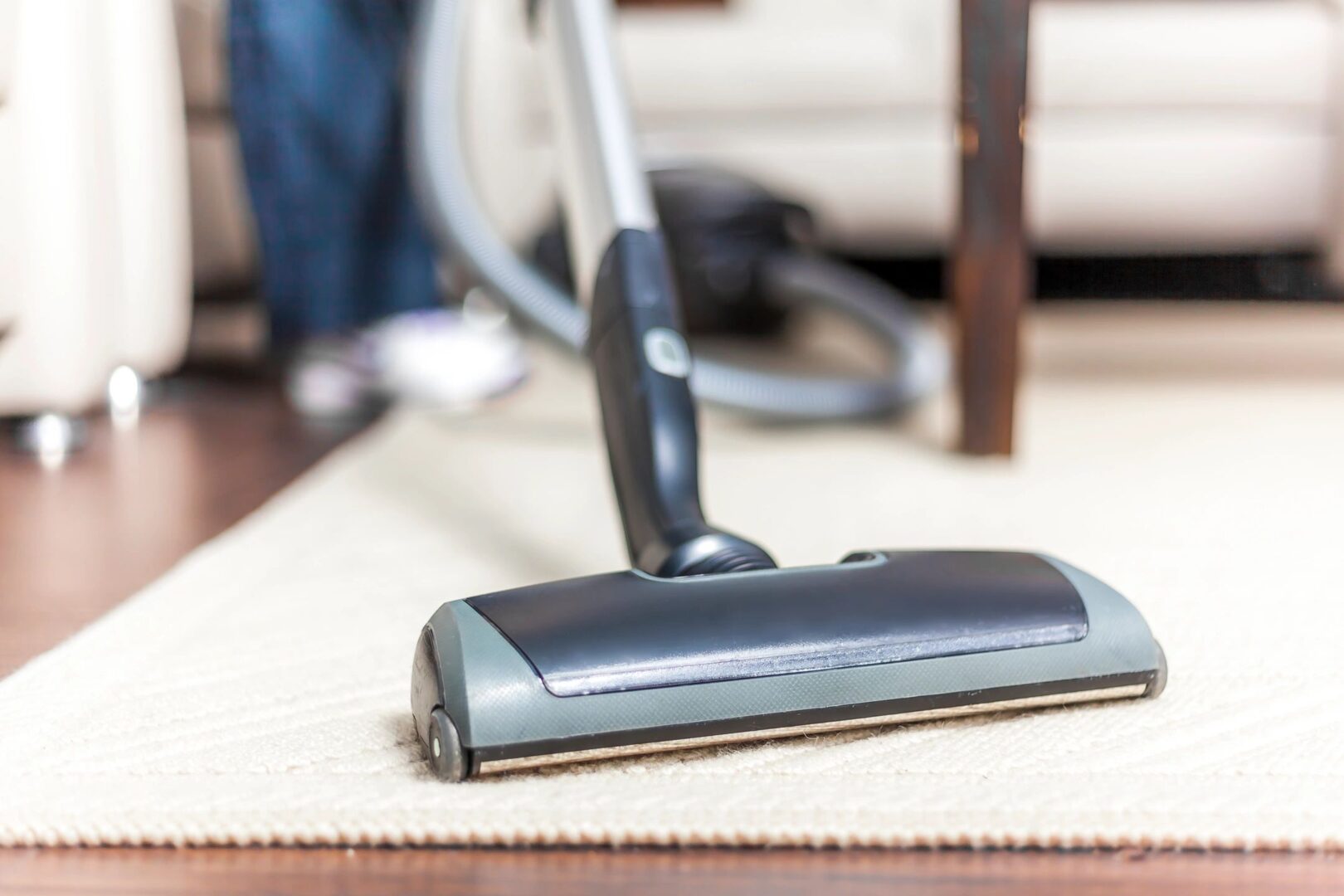 A vacuum cleaner is on the floor near a chair.