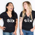 Two women wearing black shirts with the word six on them.