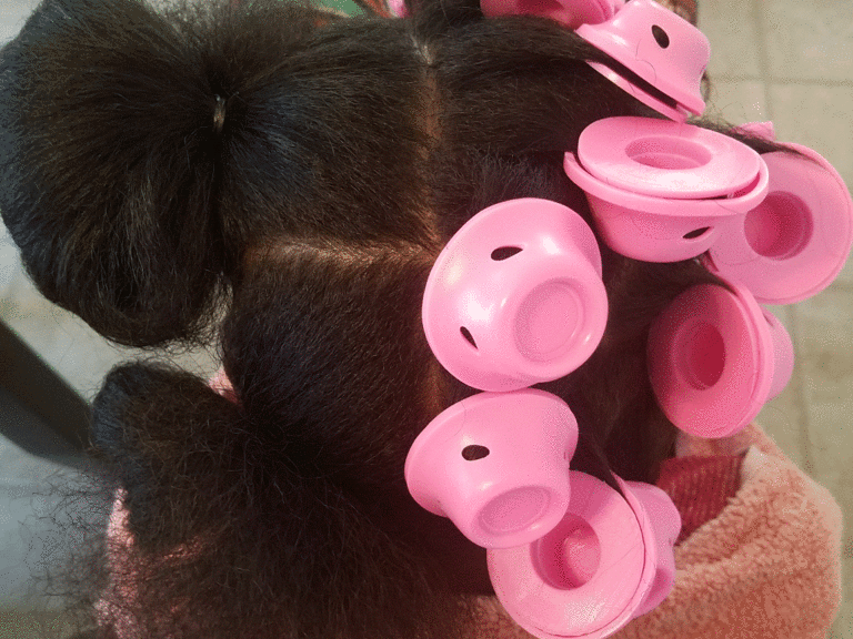 A black cat with pink hair clips on its head.