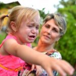 A little girl crying next to an older woman.