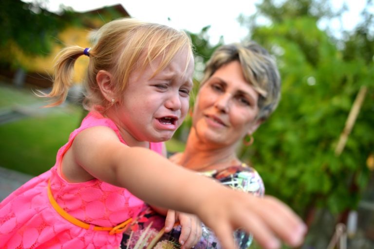 A little girl crying next to an older woman.