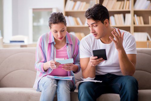 A man and woman sitting on the couch looking at their phones.