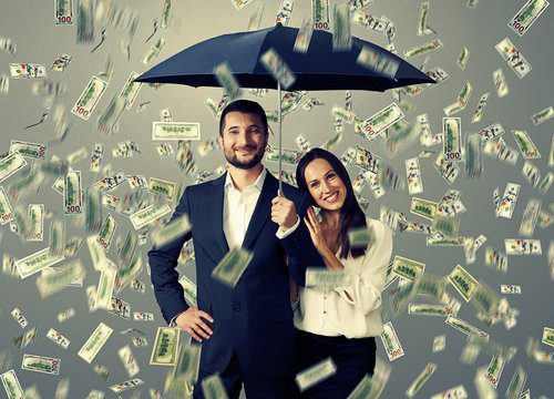 A man and woman under an umbrella with money falling from the sky.