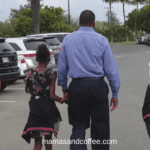 A man and woman holding hands while walking down the street.