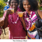 Two women are holding drinks and wearing leis.