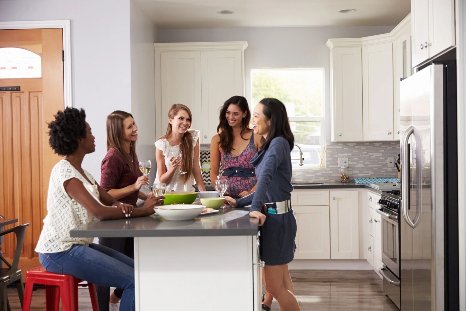 A group of women in the kitchen talking to each other.