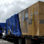 A truck with boxes on it's back and blue tarp covering the sides.