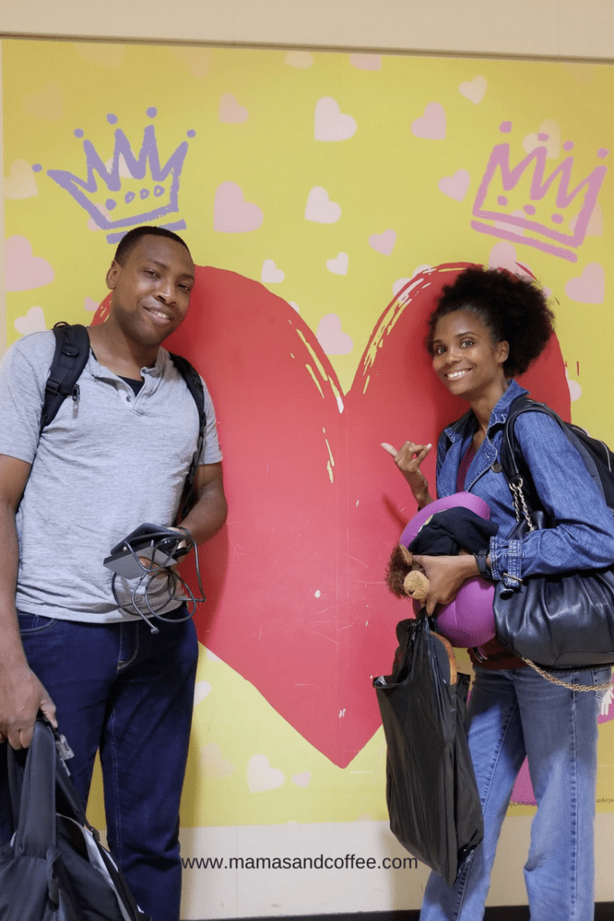 Two people posing for a picture in front of a heart mural.
