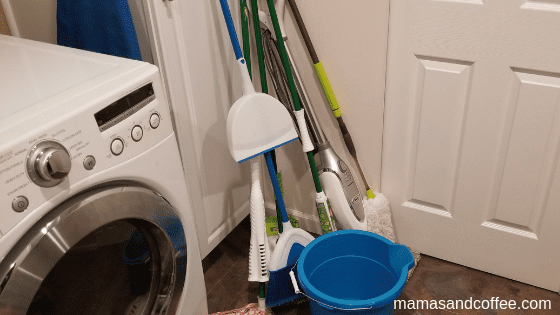 A bunch of cleaning supplies sitting in front of the washer.