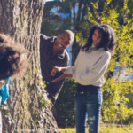 A man and woman standing next to a tree.