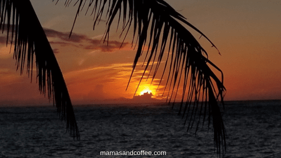 A sunset with the sun setting over the ocean.