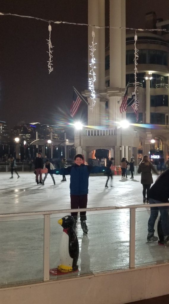 A boy is standing in the middle of an ice rink.