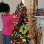 A girl is decorating the christmas tree.