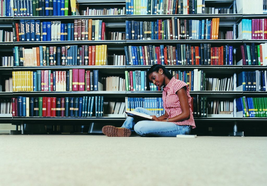 A woman sitting on the floor in front of some books