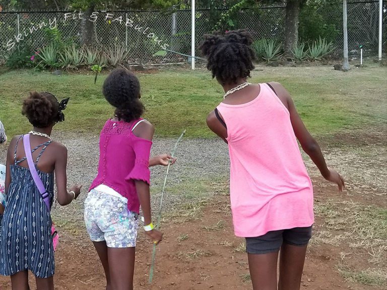 Three girls are playing with a frisbee in the dirt.