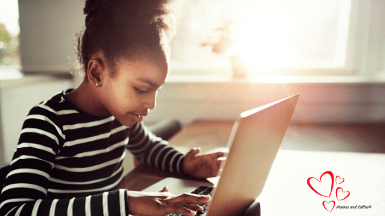 A young girl is using her laptop at the table.