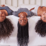 Three women laying on a bed with their hair in the air.