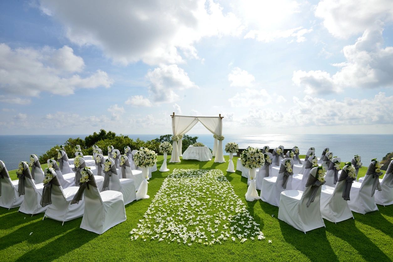 A wedding ceremony with white chairs and flowers.