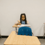 A young girl sitting at her desk writing.