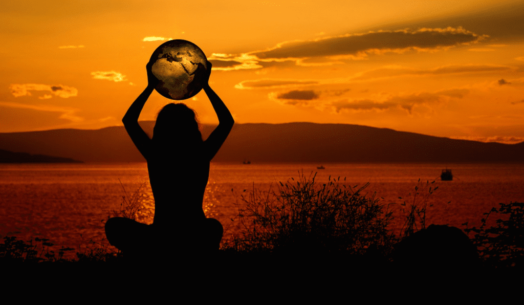 A person holding up the earth in front of an orange sky.