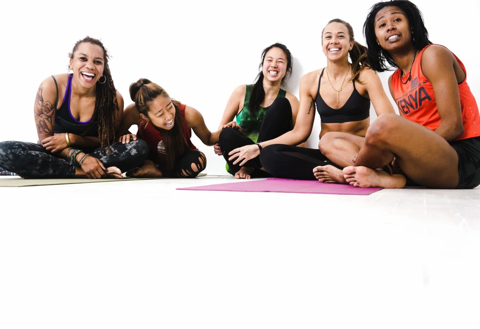 A group of women sitting on the ground in yoga poses.