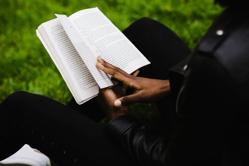 A person sitting on the ground reading a book.