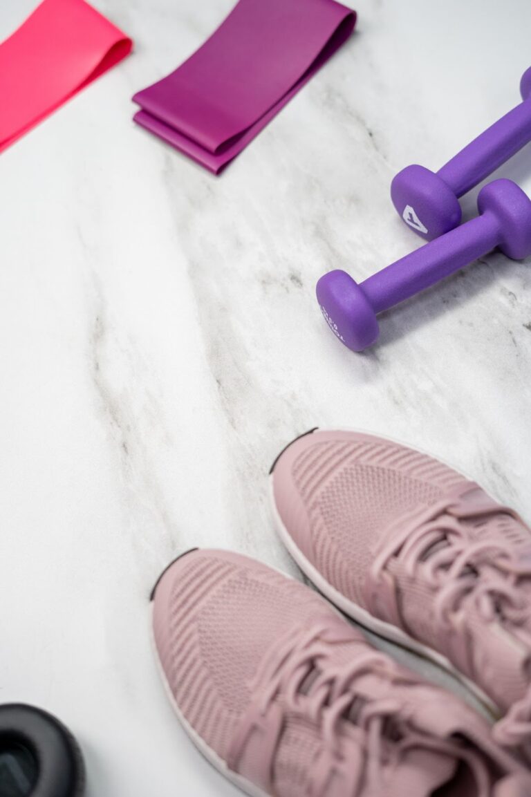A pair of pink shoes and purple dumbbells on the ground.