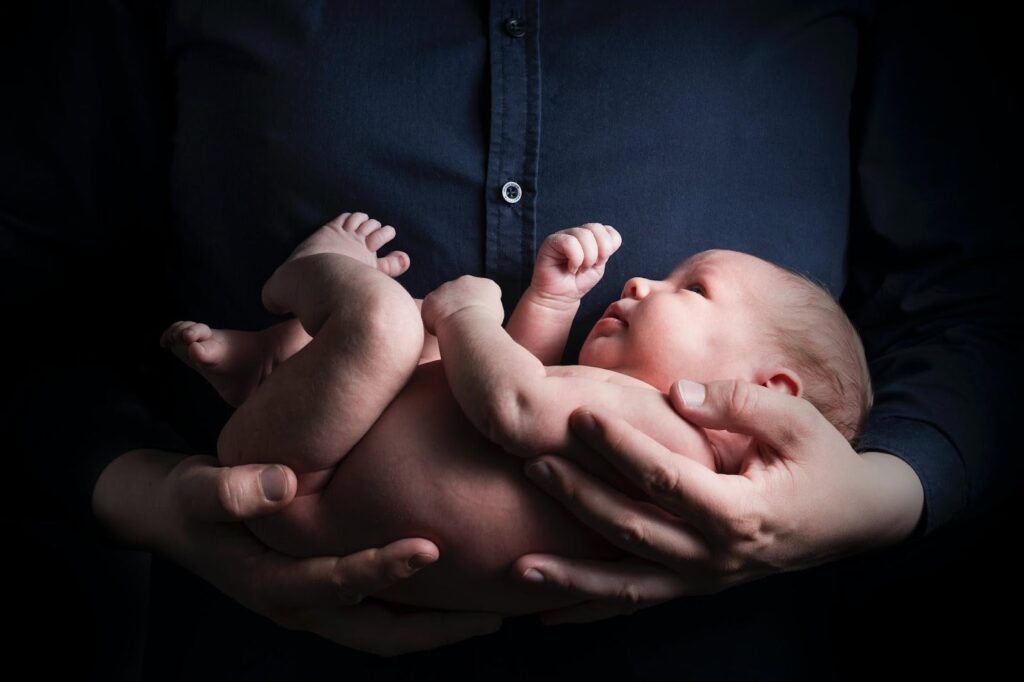 A baby is held in the arms of an adult.