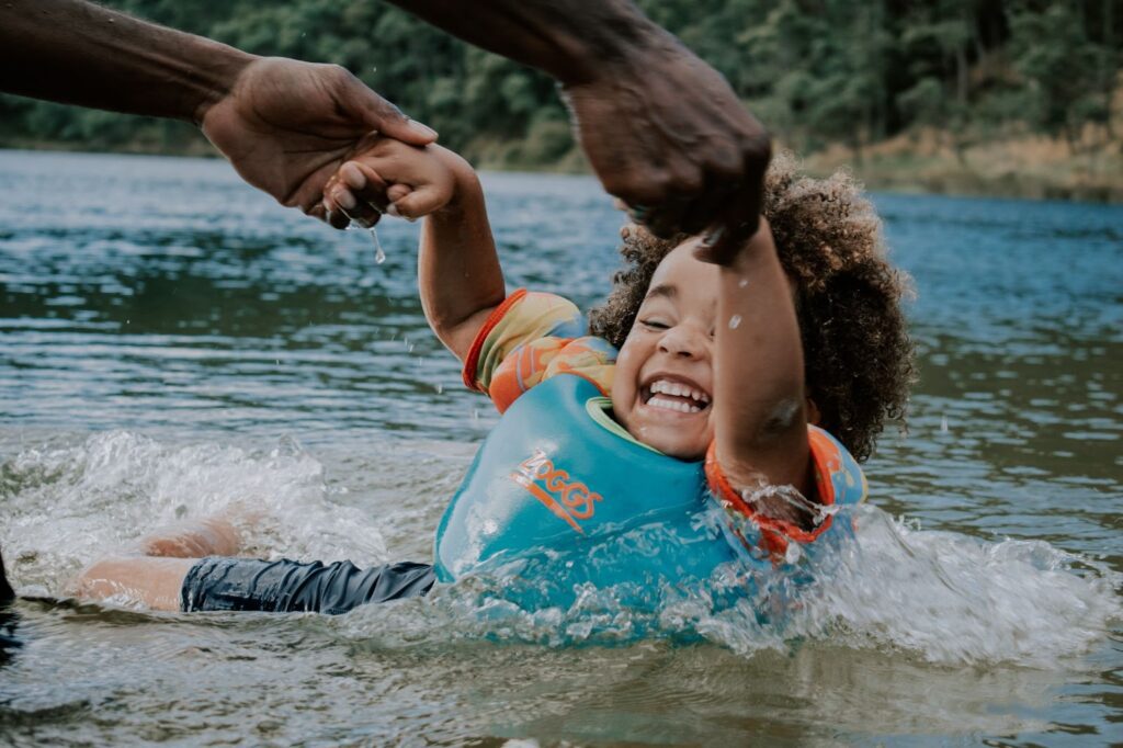 A child is being pushed in the water by an adult.