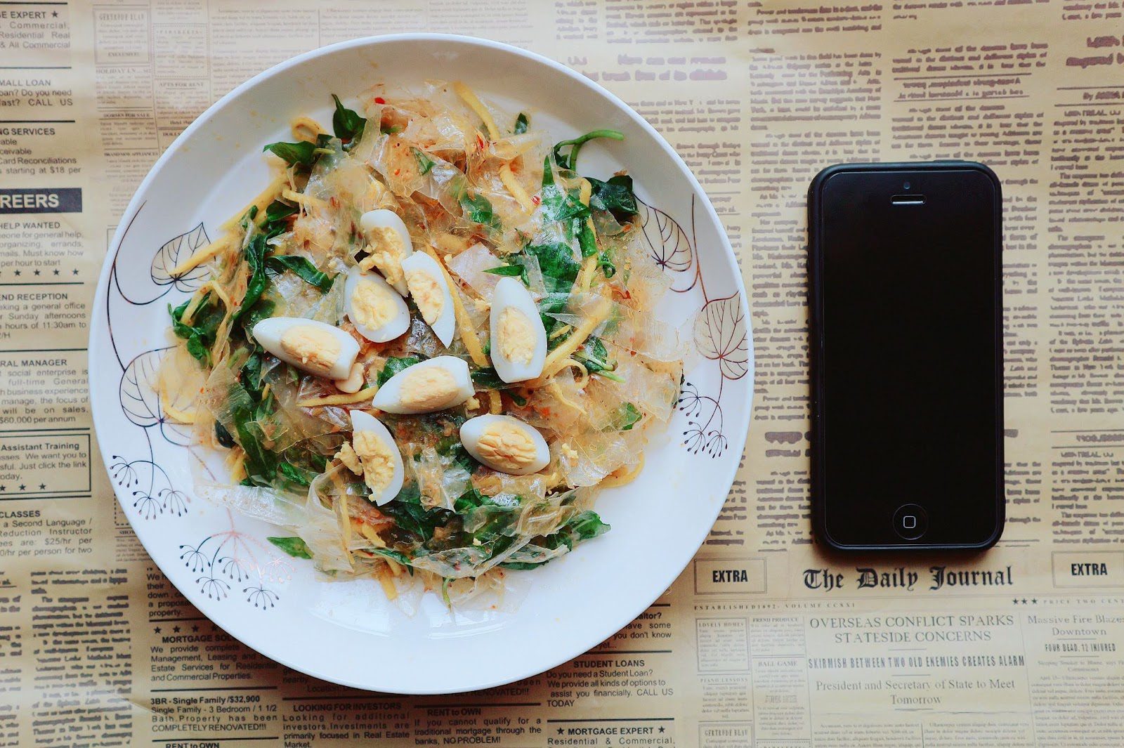 A plate of food beside a smartphone.