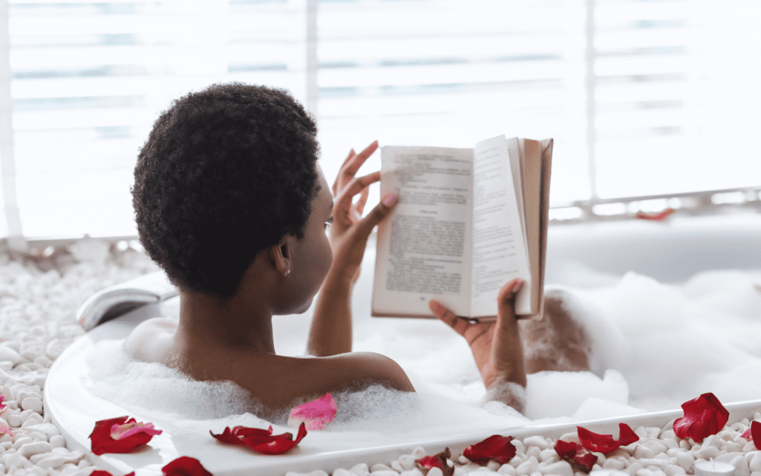 A woman reading a book in a bathtub with rose petals.
