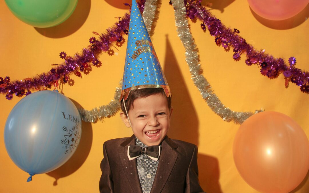 A young boy wearing a birthday hat.